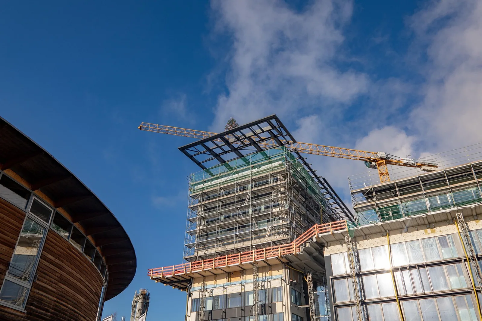 Neubau mit Glasfassade im Bau, Kran und Gerüst davor