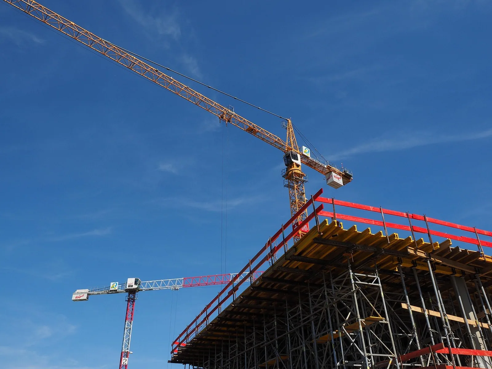 Autokran über einer Geschossdecke mit roter Randschalung vor blauem Himmel