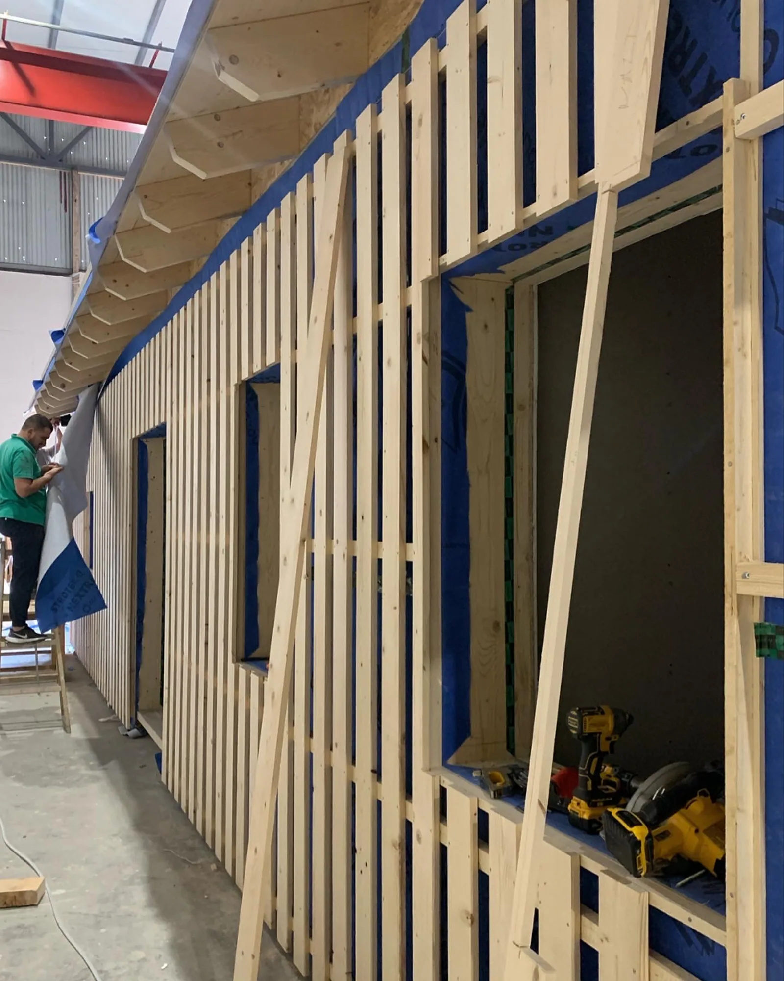 Fassadenunterkonstruktion aus Holz an einem Wandelement in der Halle