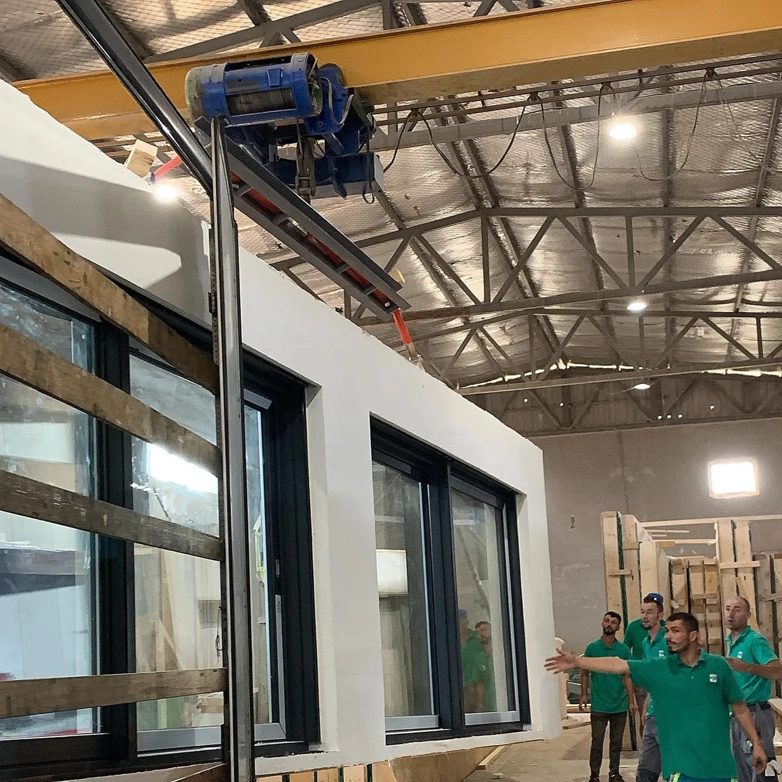 Mitarbeiter des Werks vor einem fertig ausgebauten Raummodul mit gesetzter Fensterfront